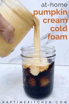 a person pouring ice cream into a mason jar with the words at - home pumpkin cream cold foam