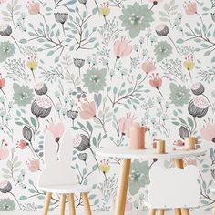 two white chairs sitting in front of a wallpapered with flowers and plants on it