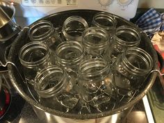 a pan filled with glass jars sitting on top of a stove