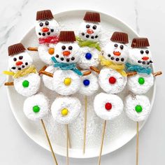 snowman marshmallows are arranged on a white plate with toothpicks