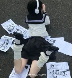 a woman sitting on the ground with headphones on and papers all around her feet