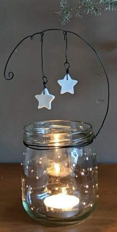 two white stars hanging from a wire above a jar filled with water and lit candles