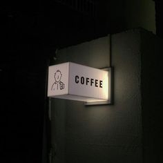 a sign on the side of a building that says coffee and is lit up at night