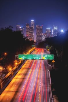 the city skyline is lit up at night as traffic passes by on an interstate highway