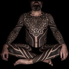 a man with tattoos sitting in the middle of his body