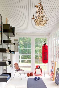 a living room filled with lots of furniture and a red boxing bag hanging from the ceiling