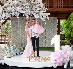 a man and woman standing on top of a stage holding their two children in pink dresses