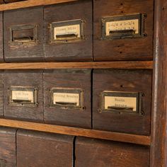 an old wooden cabinet with many drawers and labels on it's doors, showing the nameplates