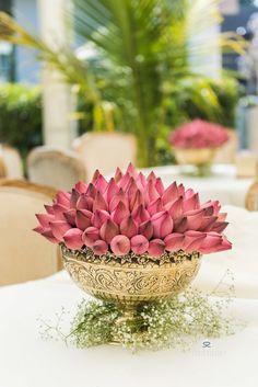 a vase filled with pink flowers sitting on top of a white table covered in greenery