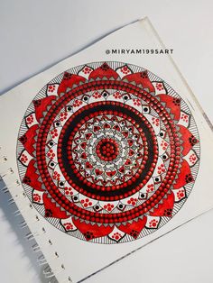 an open spiral notebook with red and black designs on the cover, sitting on a white surface