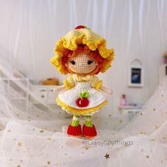 a crocheted doll is standing on a bed with white sheets and gold stars