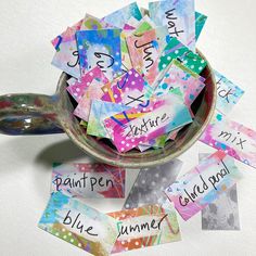 a bowl filled with lots of different colored paper notes next to a spoon and measuring spoon