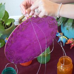 a woman is working on some crafting items with yarn and thread in front of her