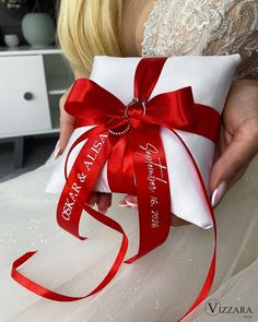 a woman holding a red and white wedding ring pillow