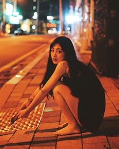 a woman kneeling down on the side of a street