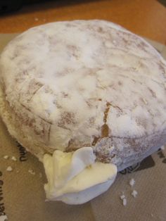 a doughnut covered in powdered sugar sitting on top of a piece of paper