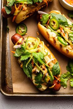 three hot dogs with toppings on a tray