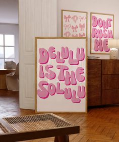 two pink posters on the wall in a room with wooden flooring and white walls