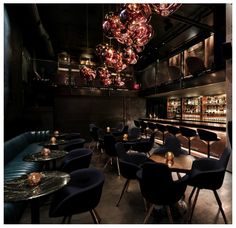 a dimly lit room with many chairs and tables in front of the bar, lights hanging from the ceiling