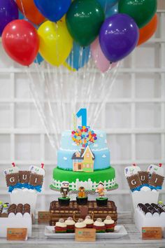 a table topped with lots of cakes and balloons