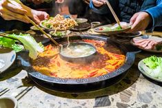 several people are serving themselves food at a table with plates and chopsticks in front of them