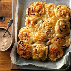 a pan filled with pastries next to a cup of coffee on a wooden table