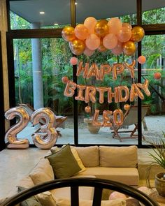 a living room filled with furniture and balloons that say happy birthday leo on the wall