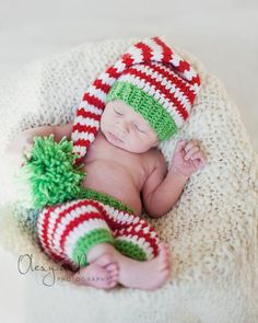 a newborn baby wearing a green and red striped hat