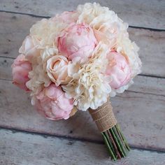 a bridal bouquet with pink and white peonies on a wooden floor in front of a door