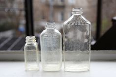 three empty glass bottles sitting on top of a window sill