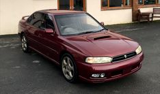 a maroon car parked in front of a building