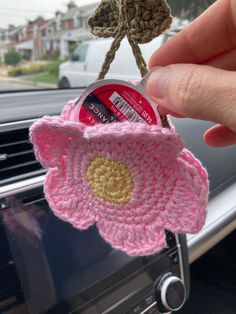 someone is holding up a pink crocheted flower in their car air freshener holder