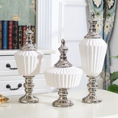 two white vases sitting on top of a table