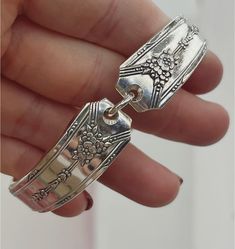 a person holding two silver bracelets in their hand