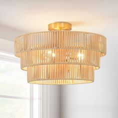 a bamboo chandelier hanging from the ceiling in a room with white walls and windows