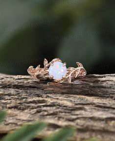 a white opal ring sitting on top of a piece of wood