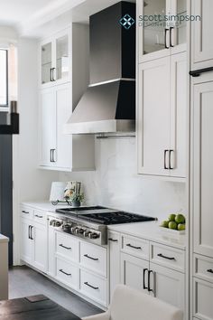 a kitchen with white cabinets and stainless steel stove top oven, hood over the range