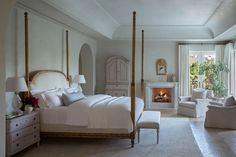 a white bedroom with a fireplace in the corner