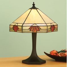 a table lamp sitting on top of a wooden table next to a bowl of fruit