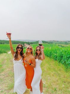 two women in dresses holding up wine glasses