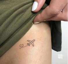 a woman's leg with a small airplane tattoo on the side of her thigh