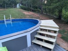 an above ground pool with steps leading up to the bottom and a wooden deck next to it