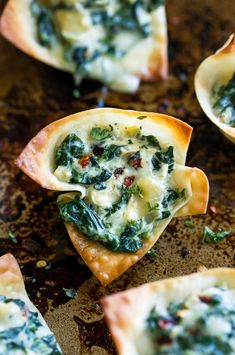 several small pieces of food with spinach and cheese in them on a baking sheet