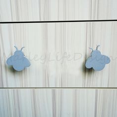 two little blue bugs are hanging on the side of a white cabinet with wood grained panels