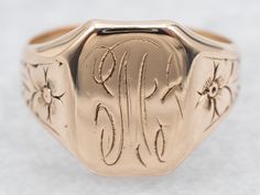 This antique signet ring has a lovely refined look to it. The sweet daisy flowers along the shoulders give just enough texture to draw the eye, without being ostentatious. We've left the original monogram "M" done in beautiful French Script. Please note that this signet ring has its original monogram, unfortunately, this piece cannot be altered without affecting the quality of the piece, please feel free to contact us to help you find your perfect signet ring in your style and budget! Metal: 14K Antique Rose Gold Top Measurements: 12 x 9 mm, Rectangle Monogram: "M" in French Script Ring Size: 4 Marks: "14K" Stamped on the inside band SKU #: A47281 Each piece has been identified and graded by a Graduate Gemologist who has been certified by the Gemological Institute of America (GIA). We have Victorian Signet Ring With Maker's Mark, Antique 14k Rose Gold Signet Ring, Victorian Gold Signet Ring With Initials, Antique Hallmarked Rose Gold Signet Ring, Antique 14k Gold Signet Ring With Hallmarks, Rose Gold Top, M Monogram, French Script, Signet Rings