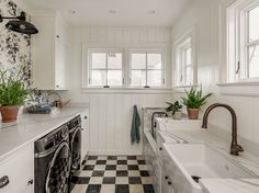 a white kitchen with black and white checkered flooring, an oven, dishwasher and sink