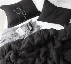 an unmade bed with black comforter and pillows