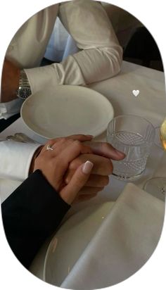 two people sitting at a table with wine glasses in front of them and plates on the table