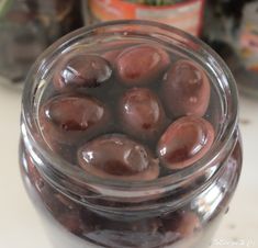 a jar filled with chocolate covered cherries on top of a white counter next to bottles