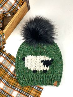 a green knitted hat with a black fur pom